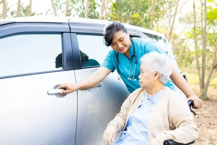 Caregiver helping a senior into a vehicle