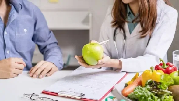 Doctor holding an apple during nutrition counseling